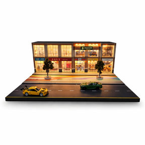 Miniature street scene with lit storefronts and two diecast cars for Shou Cang Jia IMX2569