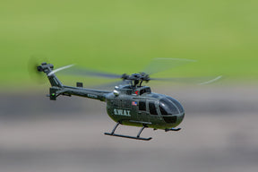 Black remote-controlled helicopter flying outdoors against a green background for Rage R/C RGR6053
