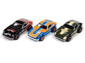 Three slot cars: black, orange/blue, and green for Auto World SCM117