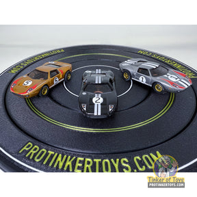 Three slot car race cars on a circular track: silver, black, and gold for Auto World CP7989–CP7991