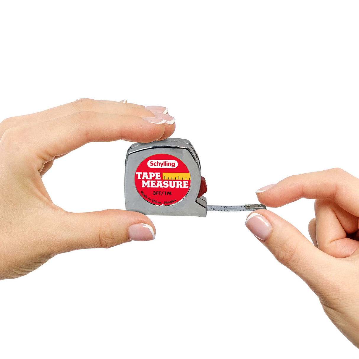 Two hands holding a miniature tape measure with a metallic body. The tape measure, branded "Schylling," has a partially