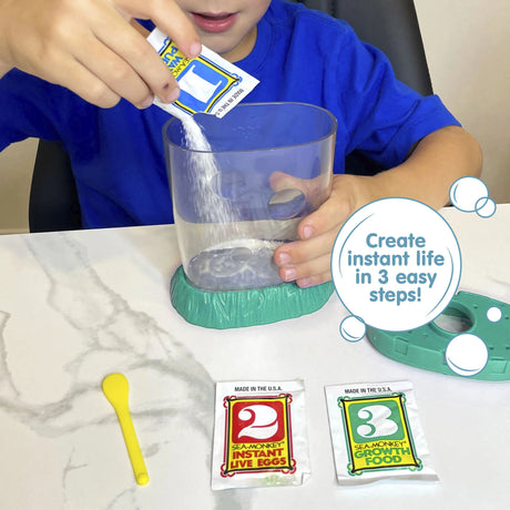 A child wearing a blue shirt is holding the aquarium with one hand, and pouring powder from a small packed labled with the