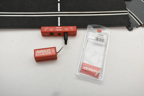 Red power supply units and clear plastic packaging on a white surface for Ninco 10304
