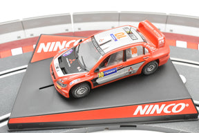 Red Mitsubishi Lancer WRC slot car on a track base for Ninco 50378