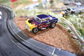 Blue and yellow 1955 Chevy Bel Air slot car on a slot car track for Slot Car 1:64 CP7726