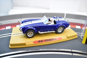 Blue AC Cobra slot car on a yellow display base for REPROTEC RT/1962