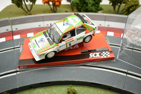 Miniature race car, white and green, on a track display for SCX A10153X3U0