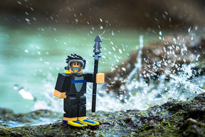 Diver minifigure holding a spear on wet rocks near splashing water for UCC