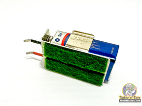 Battery tester for slot cars with visible terminals and green foam