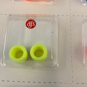 Two bright yellow silicone tire fittings in a clear plastic container for AJ's 002