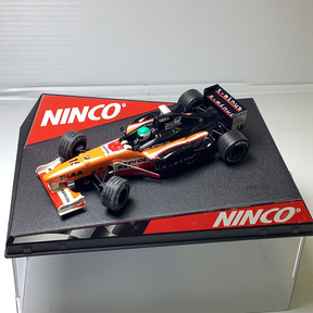 Slot car race car, orange and black, on a black display base for Ninco 50212
